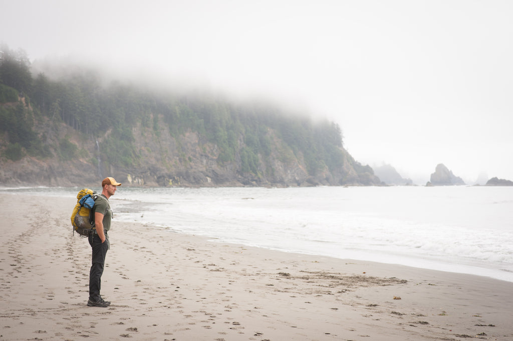 Backpacker on a weekend getaway looking at the coastline by the forested seacliffs