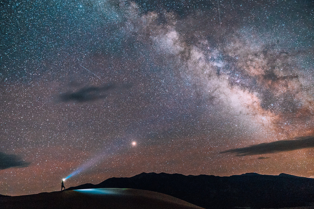 Hiker exploring the Great Sand Dunes under a starry sky