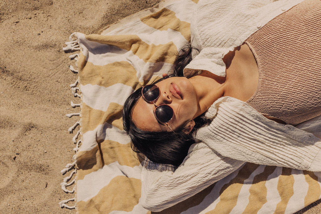 Woman basking on a beach towel on a sunny day