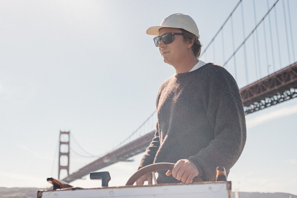 Man steering a fishing boat under the Golden Gate Bridge