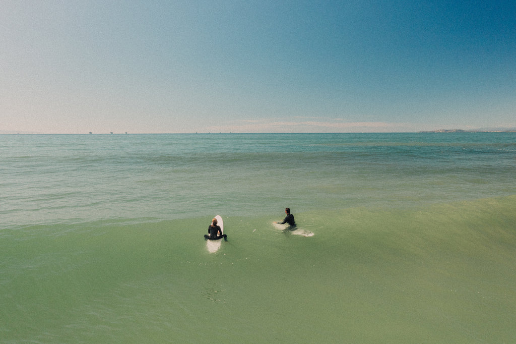 Two long surfers out on the calm ocean