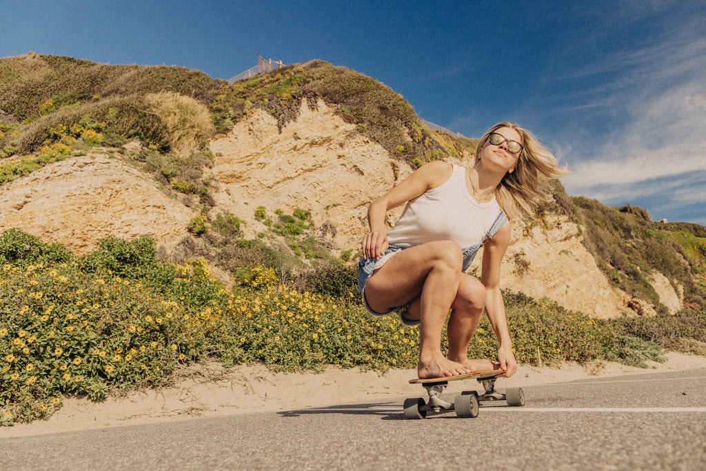 Woman skateboarding barefoot down the street