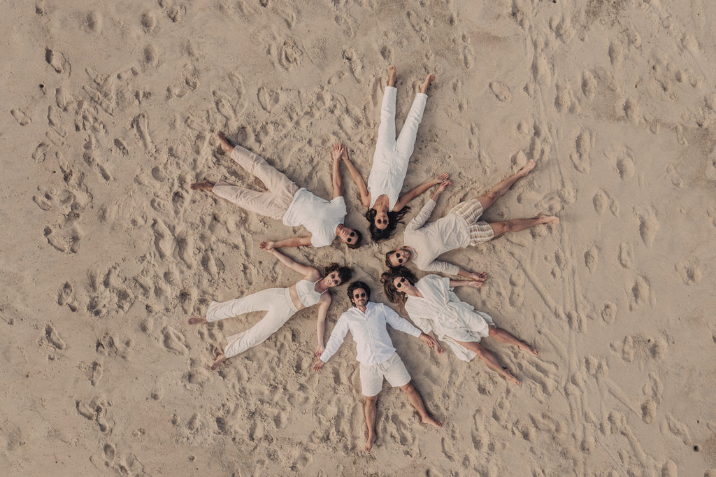 Aerial view of a group of people laying in the sand with their heads together in a star shape