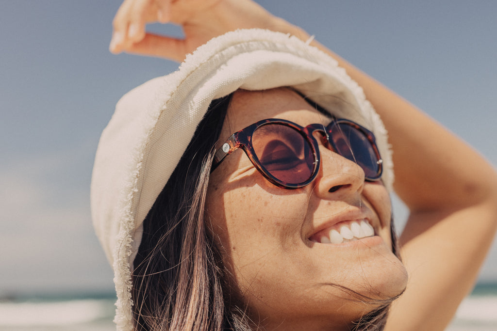 woman wearing a pair of sustainable sunglasses while basking in the sun