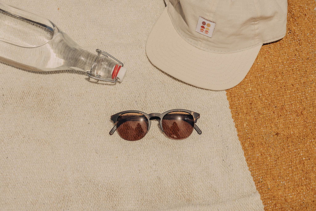 Sunglasses on a beach towel near hat and water