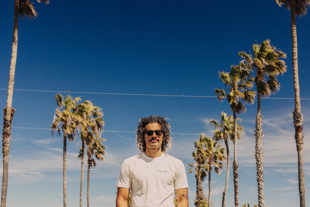 Man standing on a palm tree lined street on a sunny day