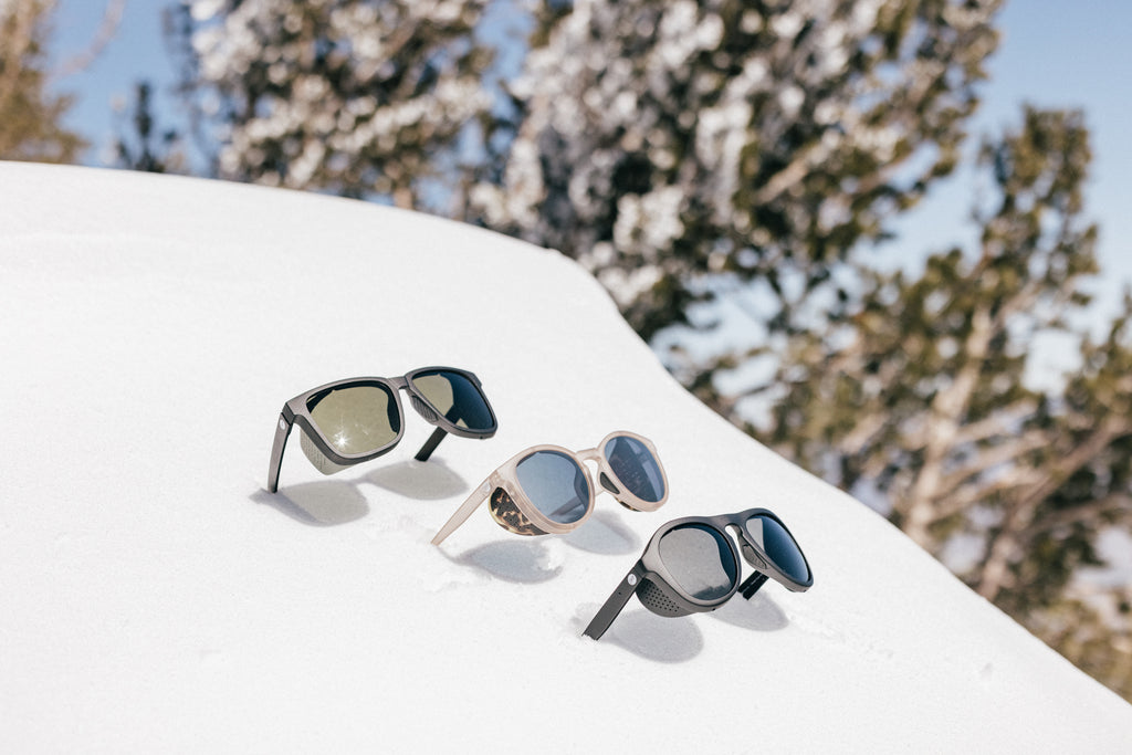 Three alpine sunglasses sticking straight out of the snow