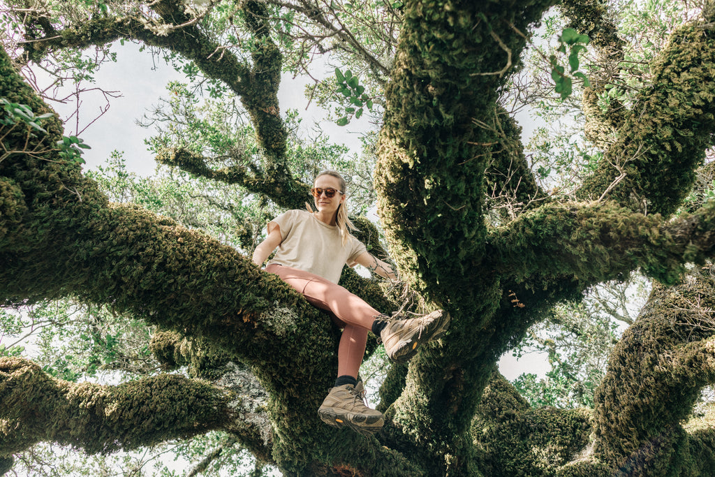 woman sitting on a mossy tree branch