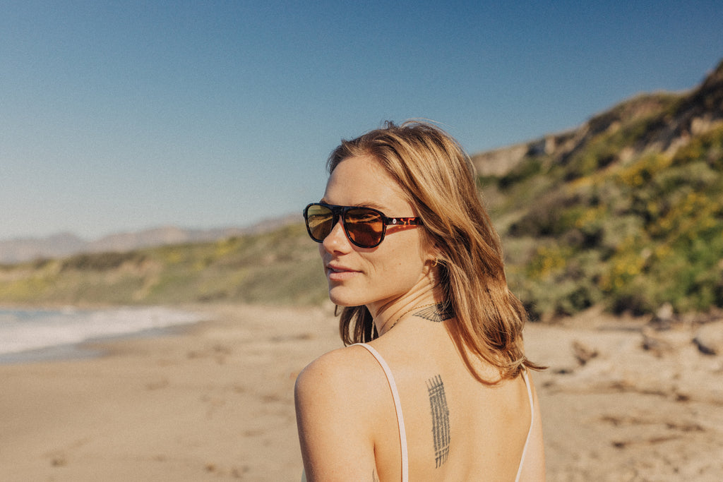 Over the shoulder look walking down the sunny beach