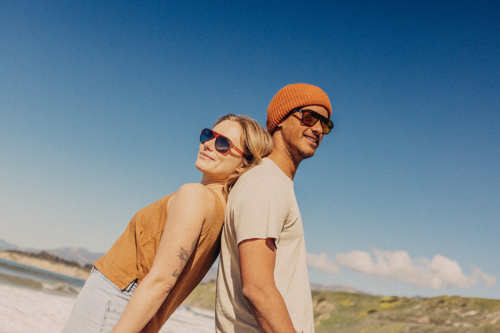 Man and woman standing back to back posing on the beach