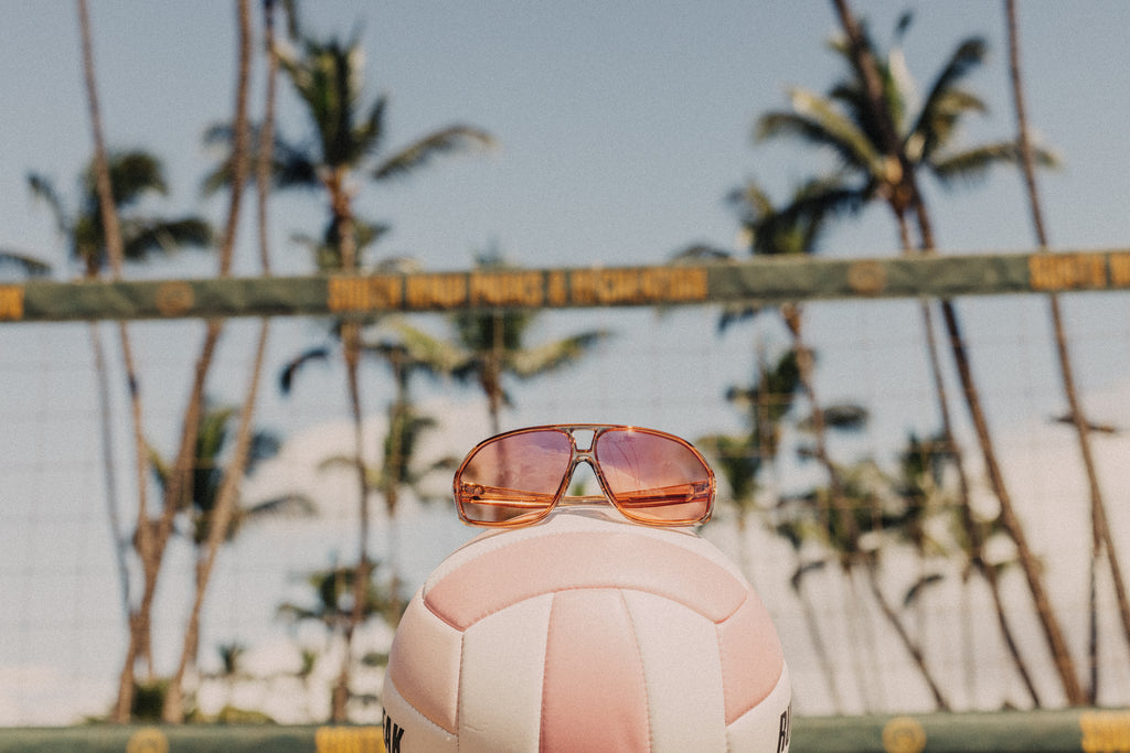 Lo light Sunski sunglasses resting on a volleyball at the beach