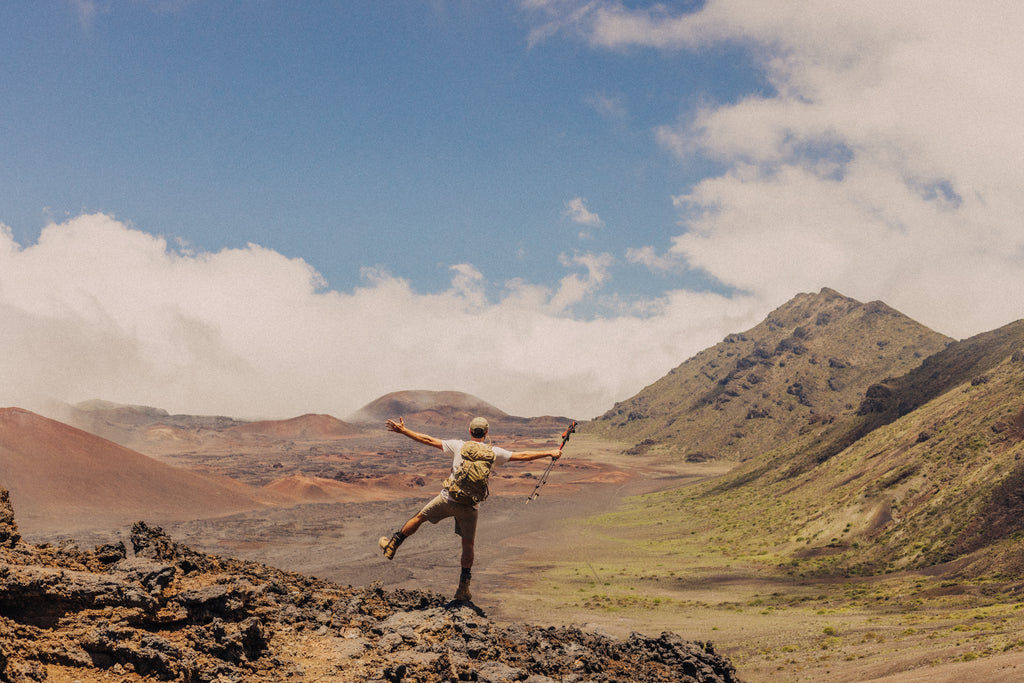 Guy standing with arms and leg out at a rocky desert vista point