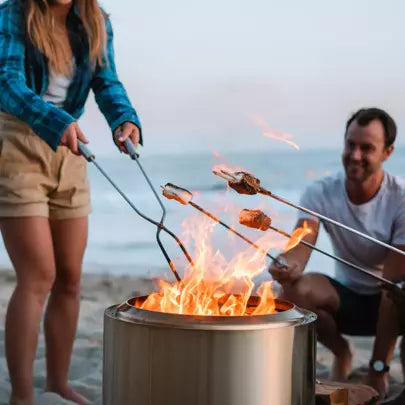 Friends at he beach using Solo Stove tools to move wood in the fire pit