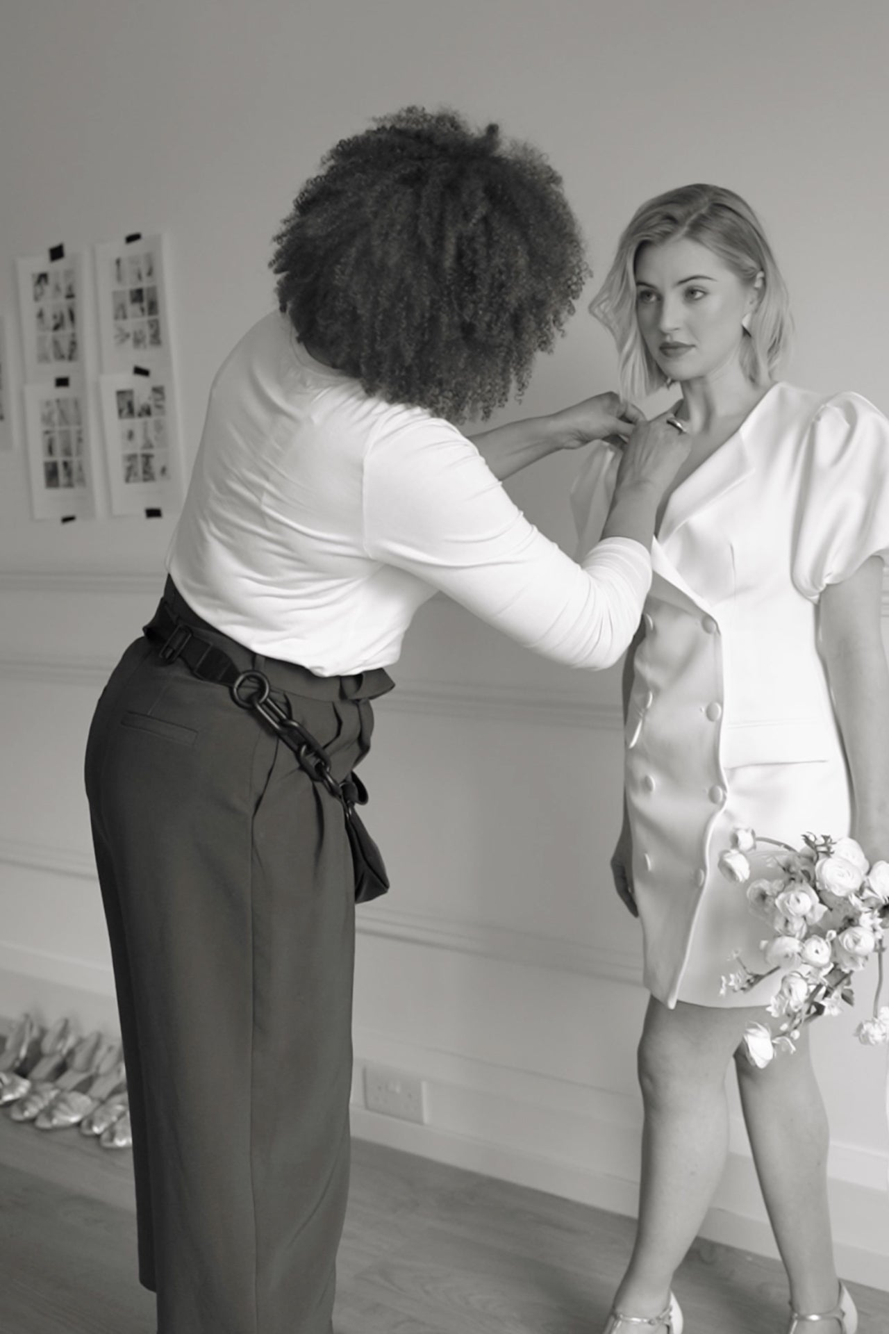 Fashion stylist adjusting model's bridal outfit