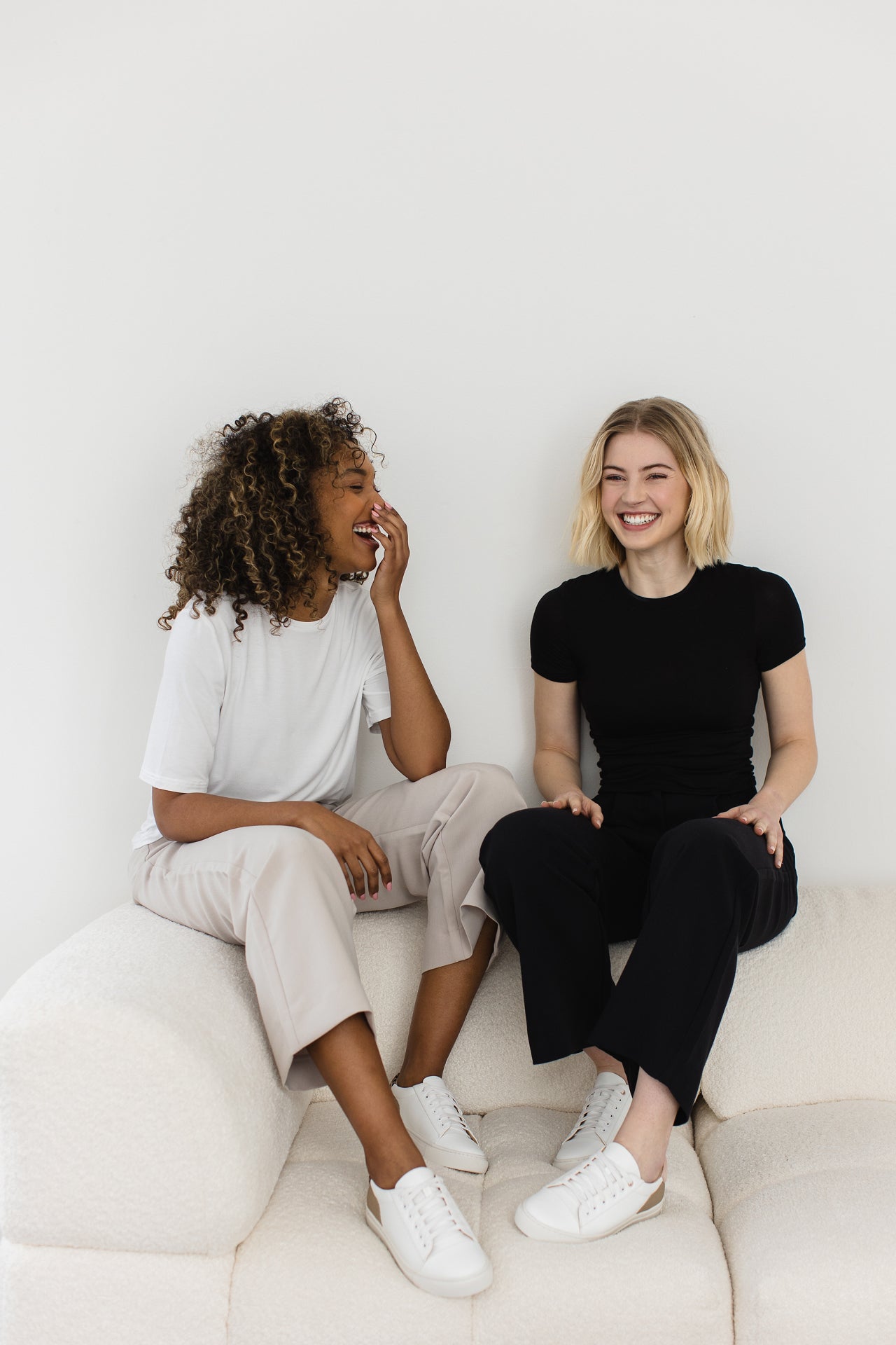Two women sitting on a sofa laughing together