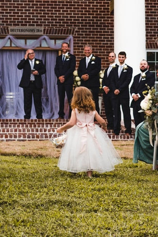 flower girl standing in front of groomsmen