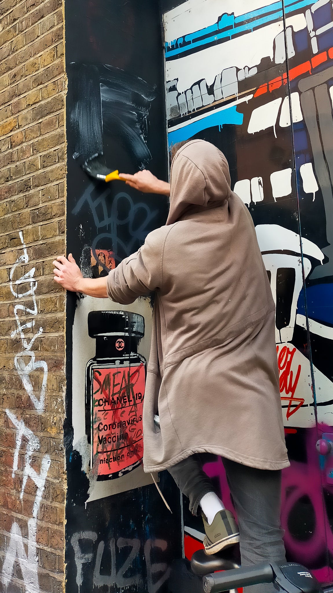 dublin artist Raise applies paste to a wall on Whitby Street