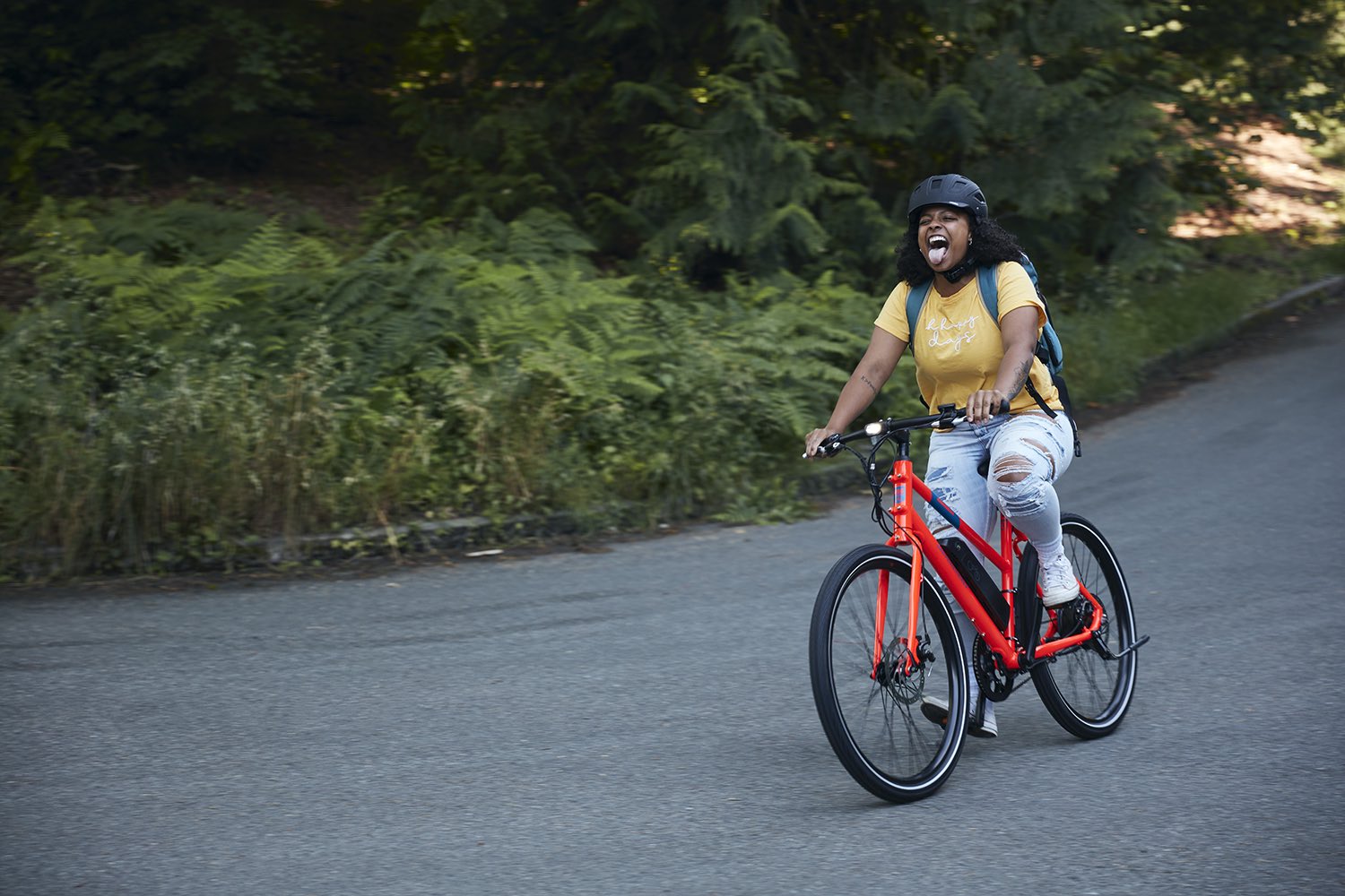 A woman rides a RadMission down a rural road.