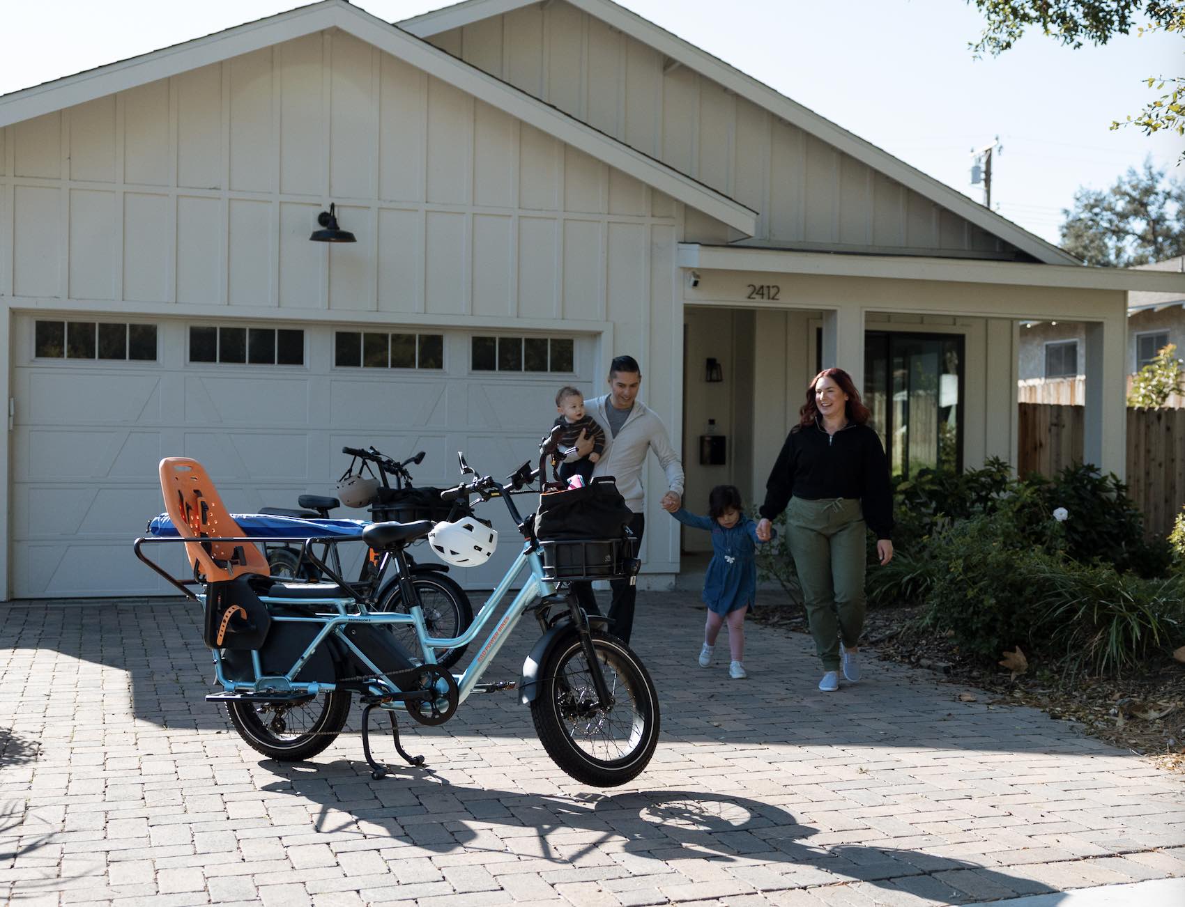 A family of three walks toward their RadWagon 5 on a suburban driveway.