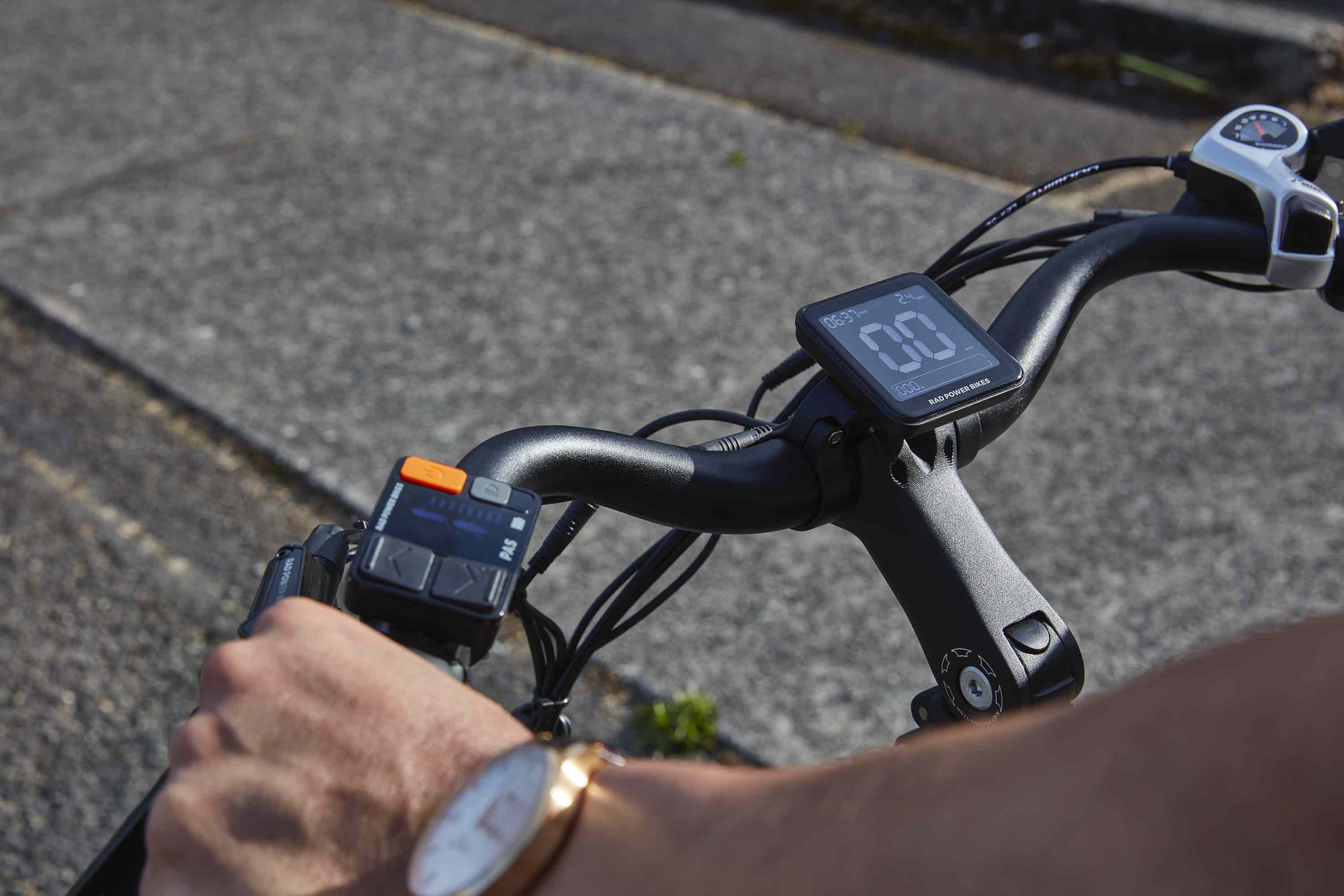 A hand rests on an the brake levers of an electric bike.