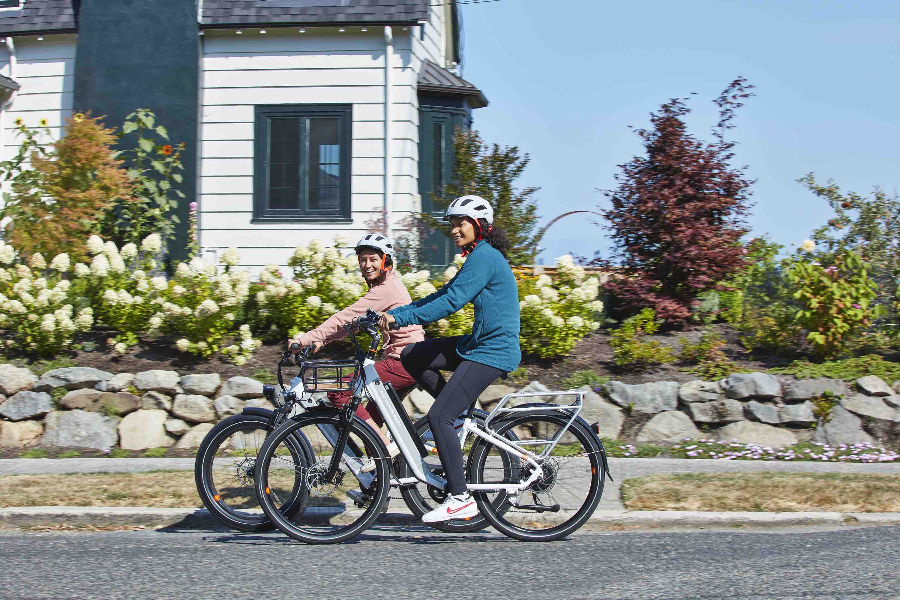 Two women ride a RadCity 5 Plus and a RadCity 6 Plus down a suburban street.