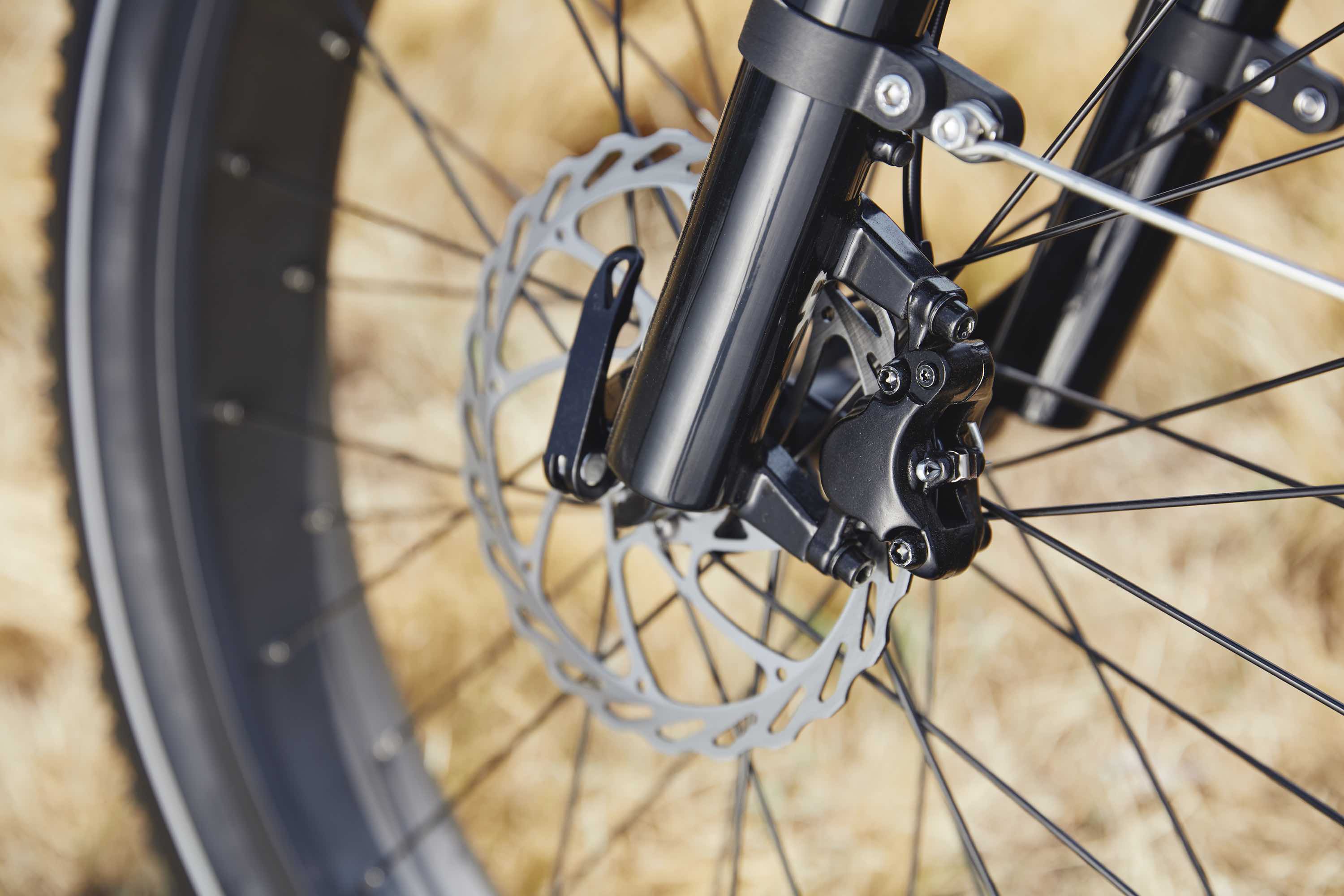 A close-up of the front wheel of an electric bike. Fall leaves are in the background.