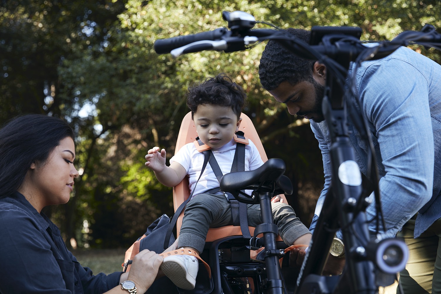 A mother and father strap their child into the Thule Yepp child seat on their RadWagon