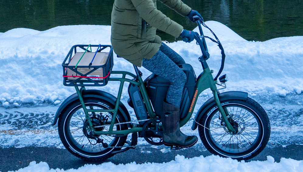 Individual rides with leggings and winter coat on their ebike in the snow.