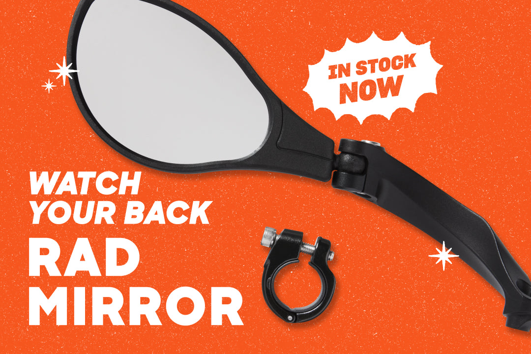 A Rad Mirror on an orange backdrop. The text overlay reads "Watch Your Back" and "In Stock Now"