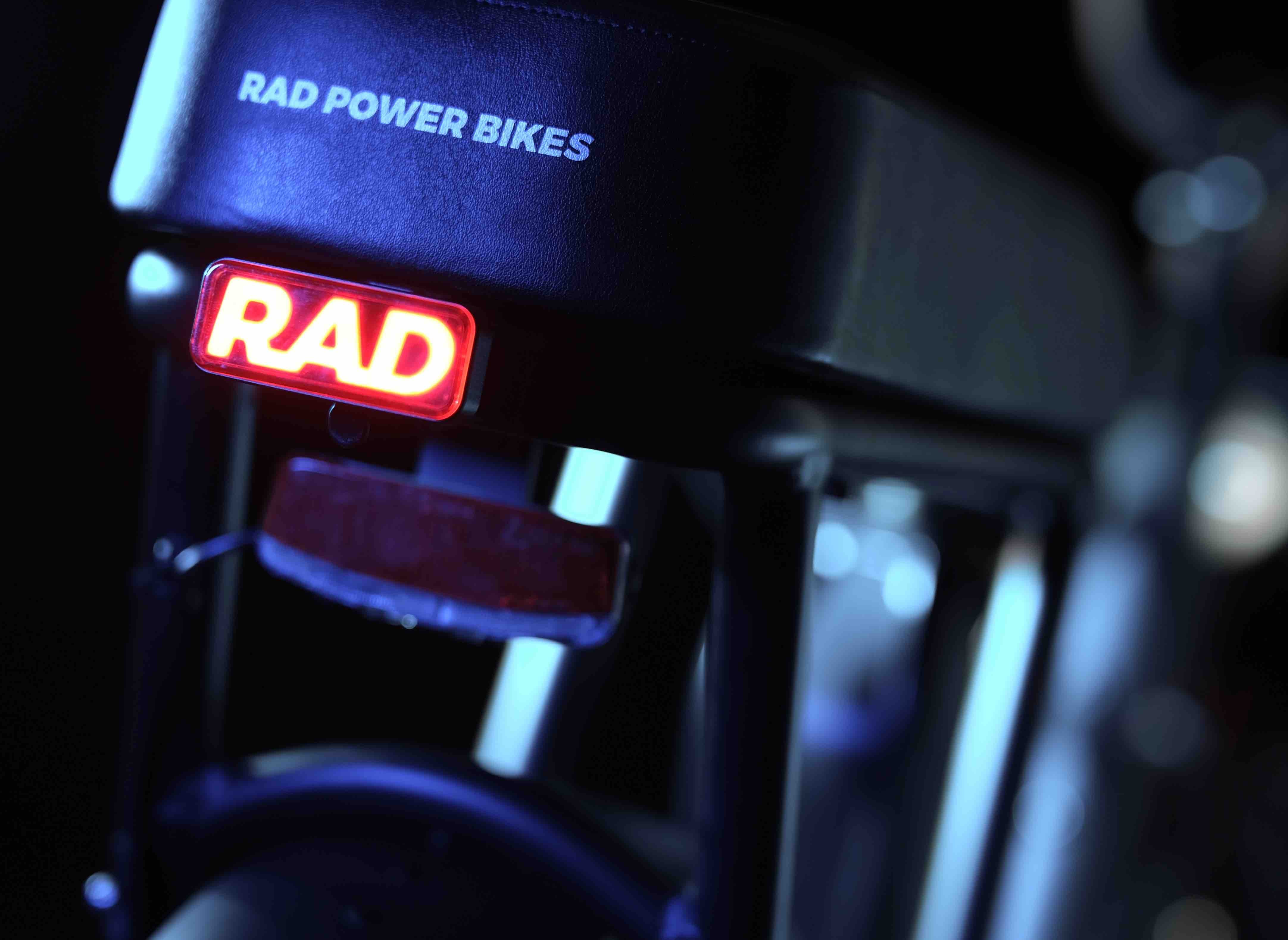 A close-up of a red tail light featuring the word "Rad" at night.