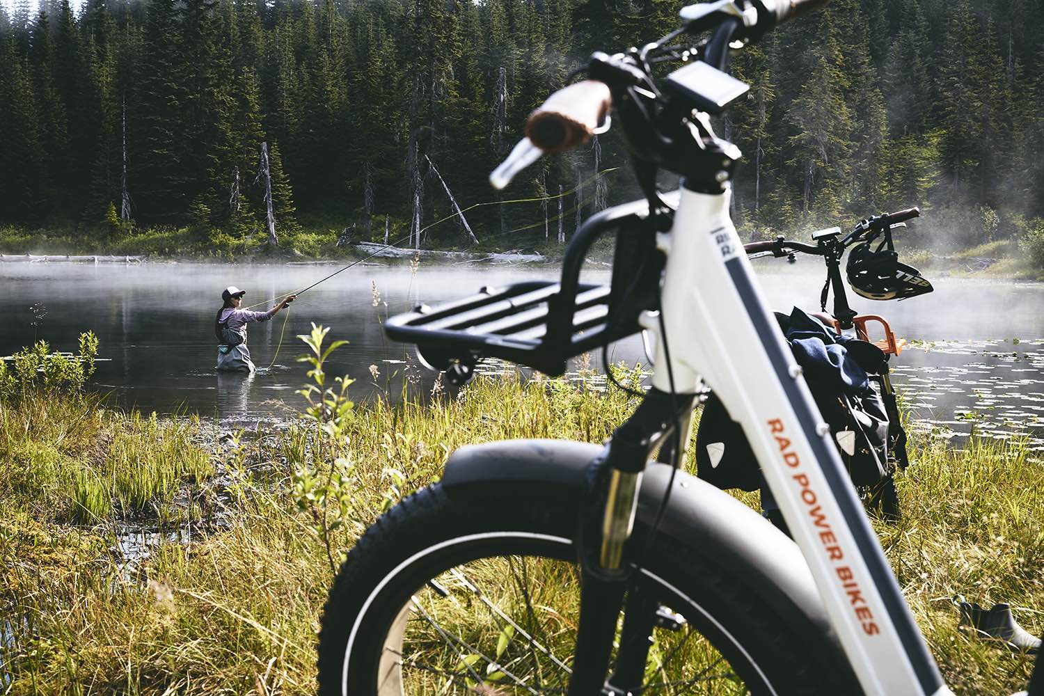 A woman fishes alongside her RadRover electric fat bike.