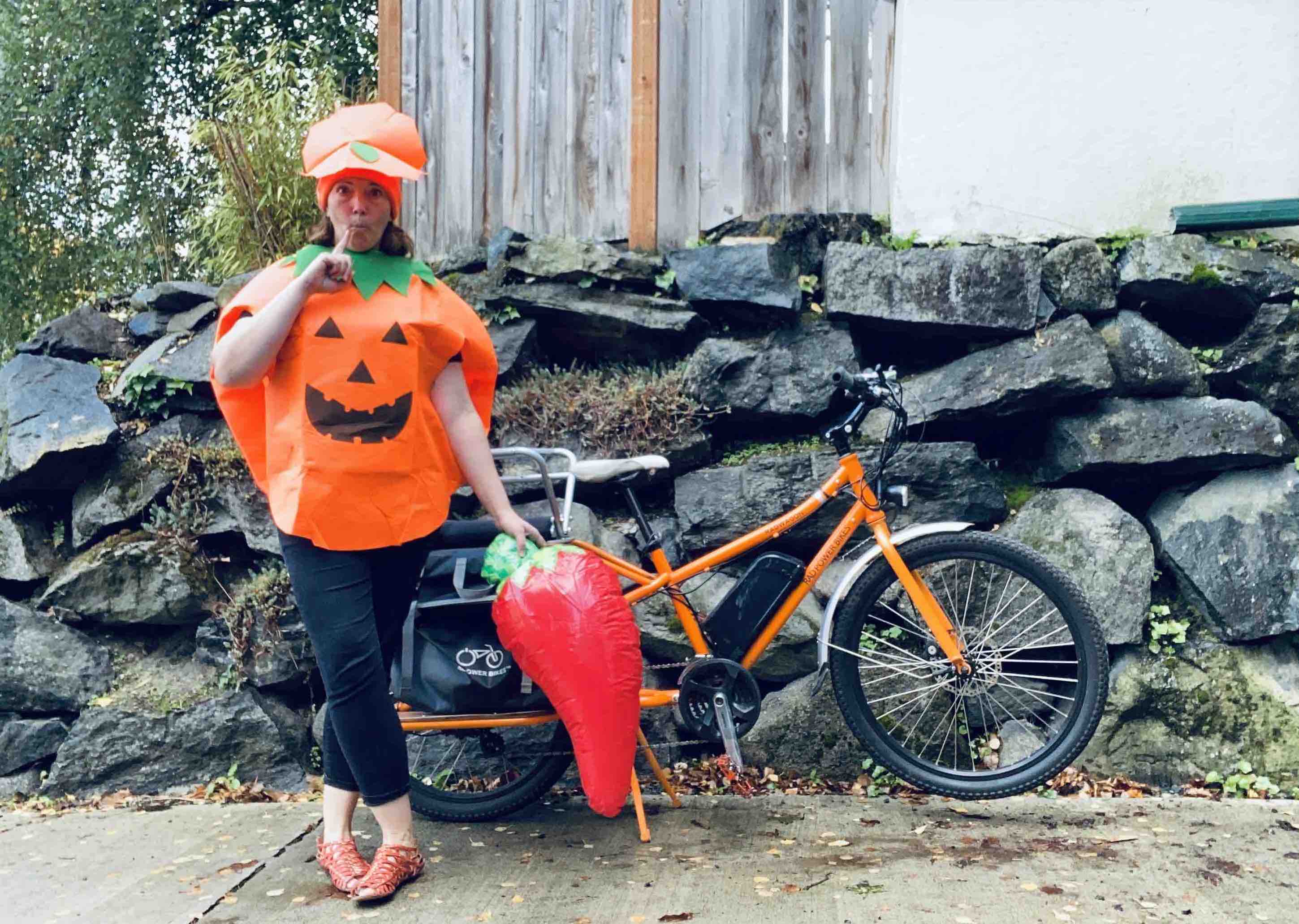 A woman dressed in a Halloween costume stands next to her RadWagon electric metro bike.