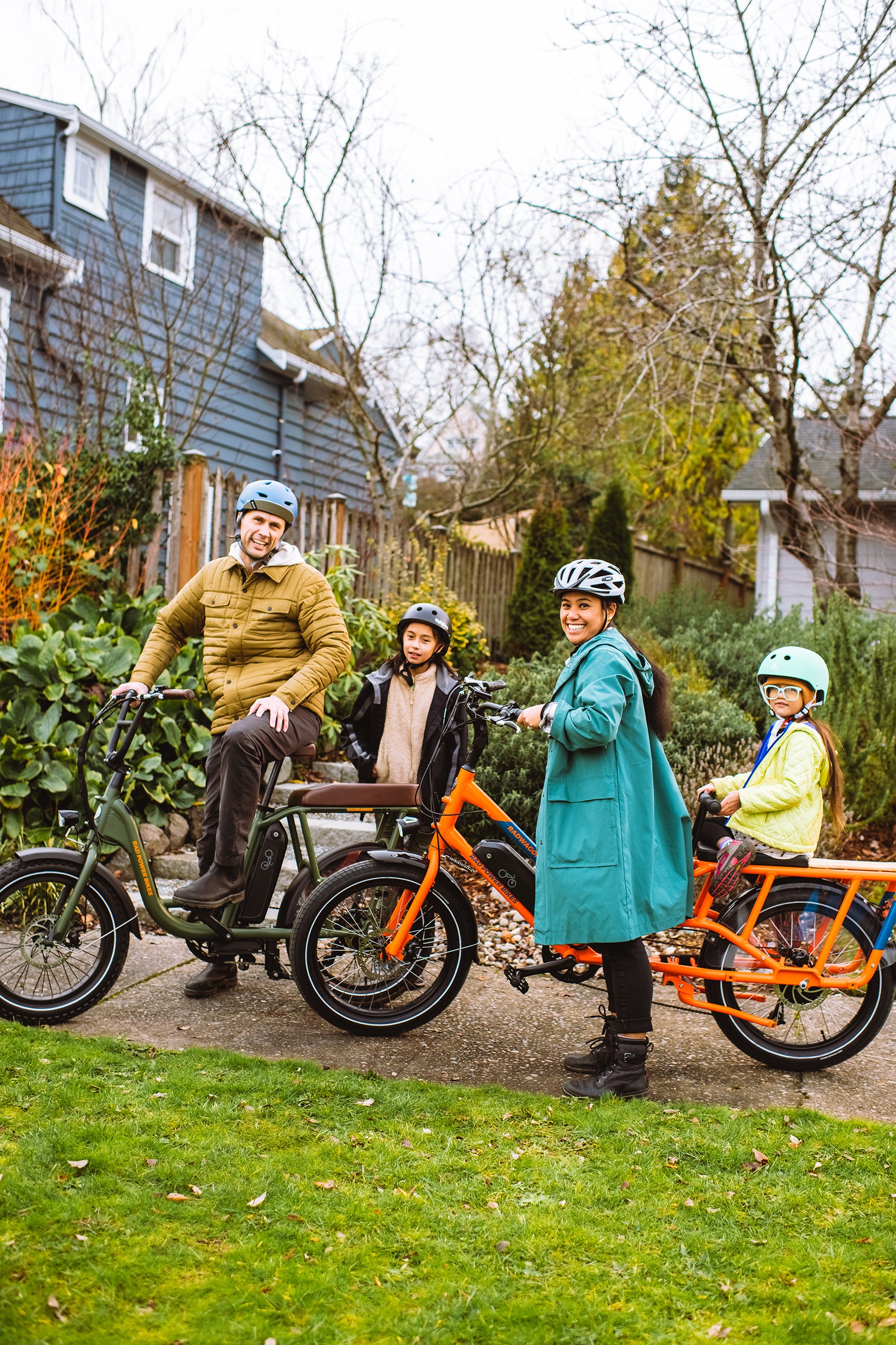 A family of four pose with their RadWagon and RadRunner outside of their home. 