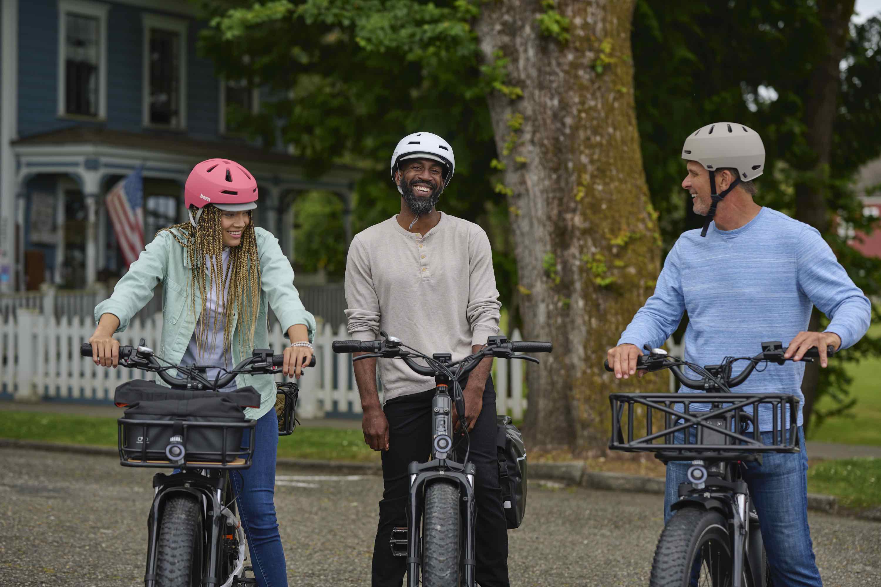 A woman and two men talk while perched on their RadRover 6 Plus electric bikes.
