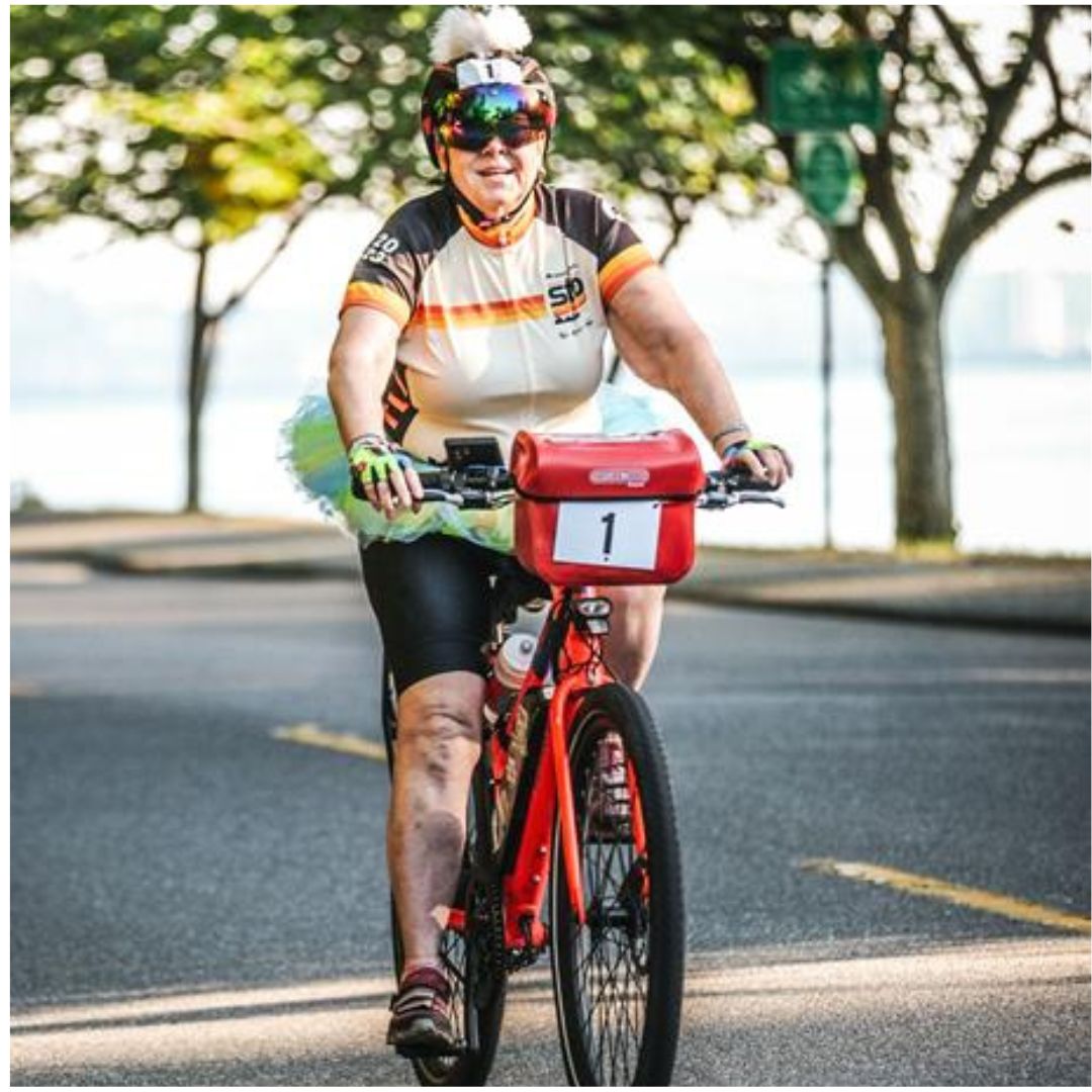 A woman in cycling gear rides a red Rad electric bike along the waterfront.