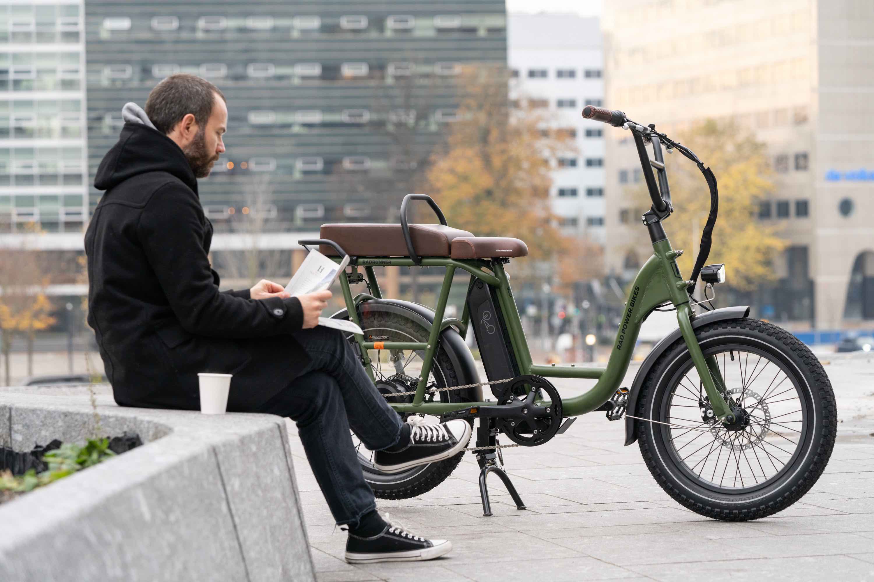 A man in fall attire reads a newspaper alongside a RadRunner 2