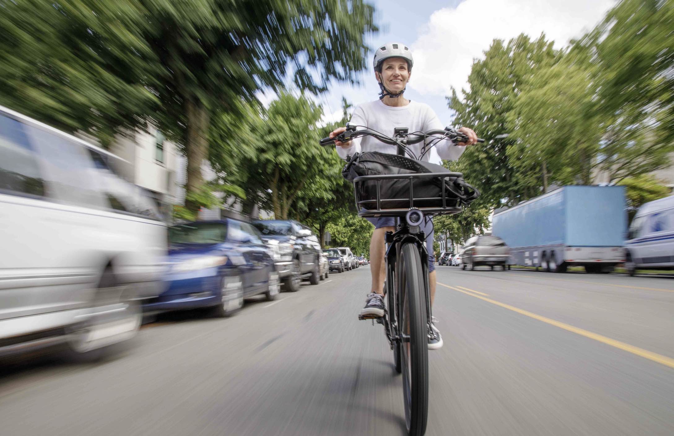 A woman commutes to work down a city street on a RadCity 5 Plus.