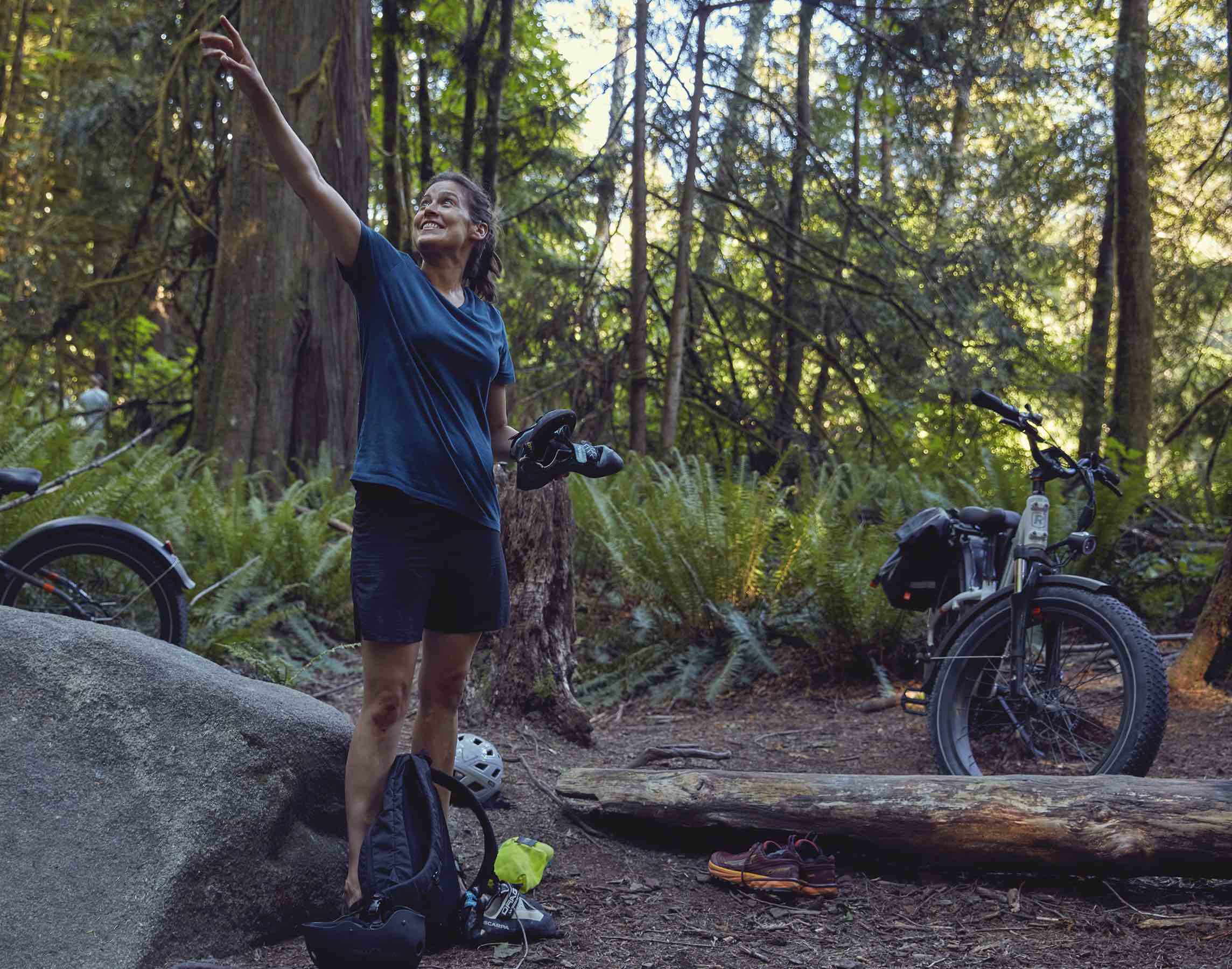 A woman goes rock climbing in the woods alongside their RadRover 6 Plus electric bike.