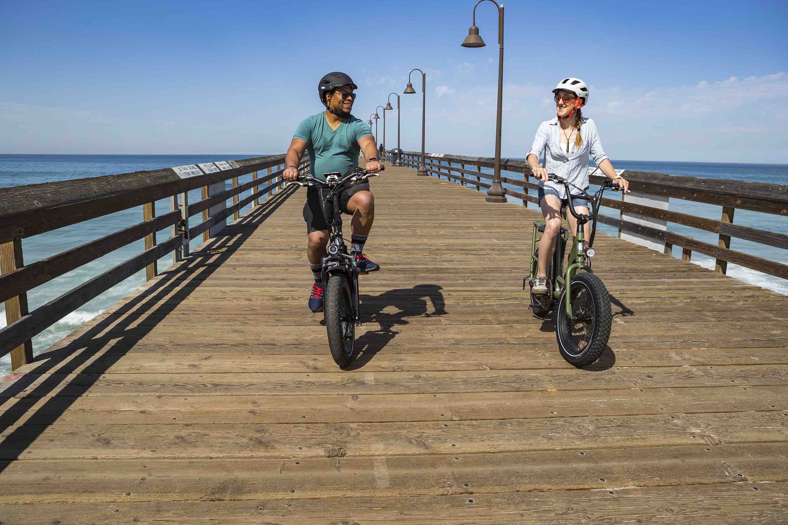 Two friends ride their electric bikes down a pier.