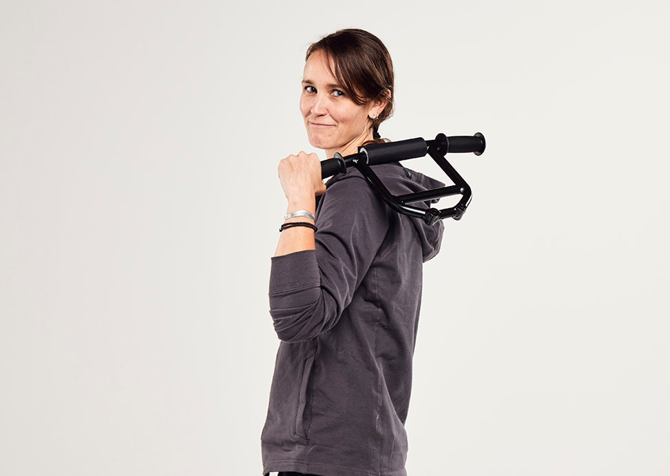 Sarah Bruce Courtney poses amid a white backdrop holding a pair of ebike handlebars.