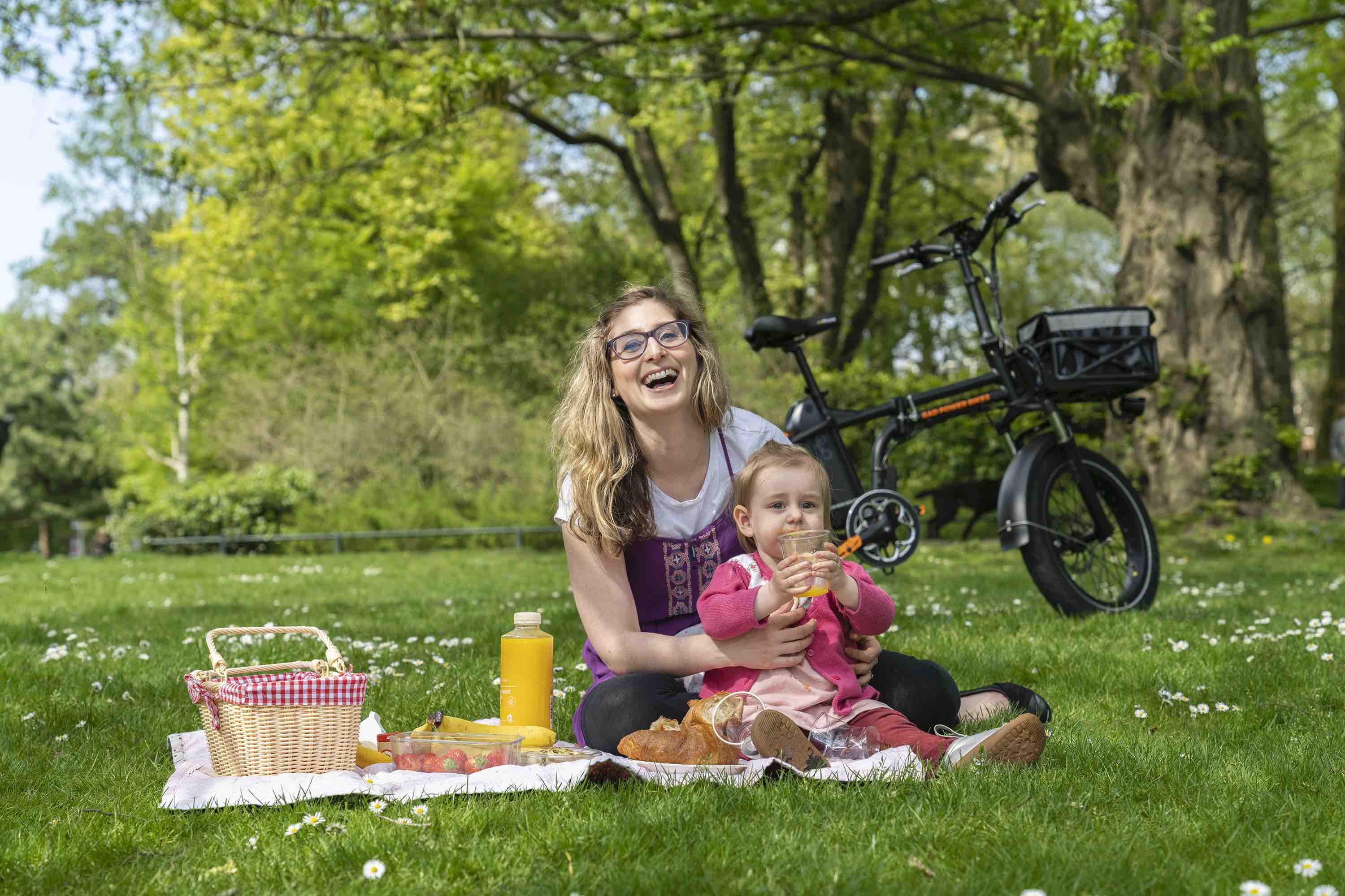 A woman and child enjoy a picnic alongside their electric bike.