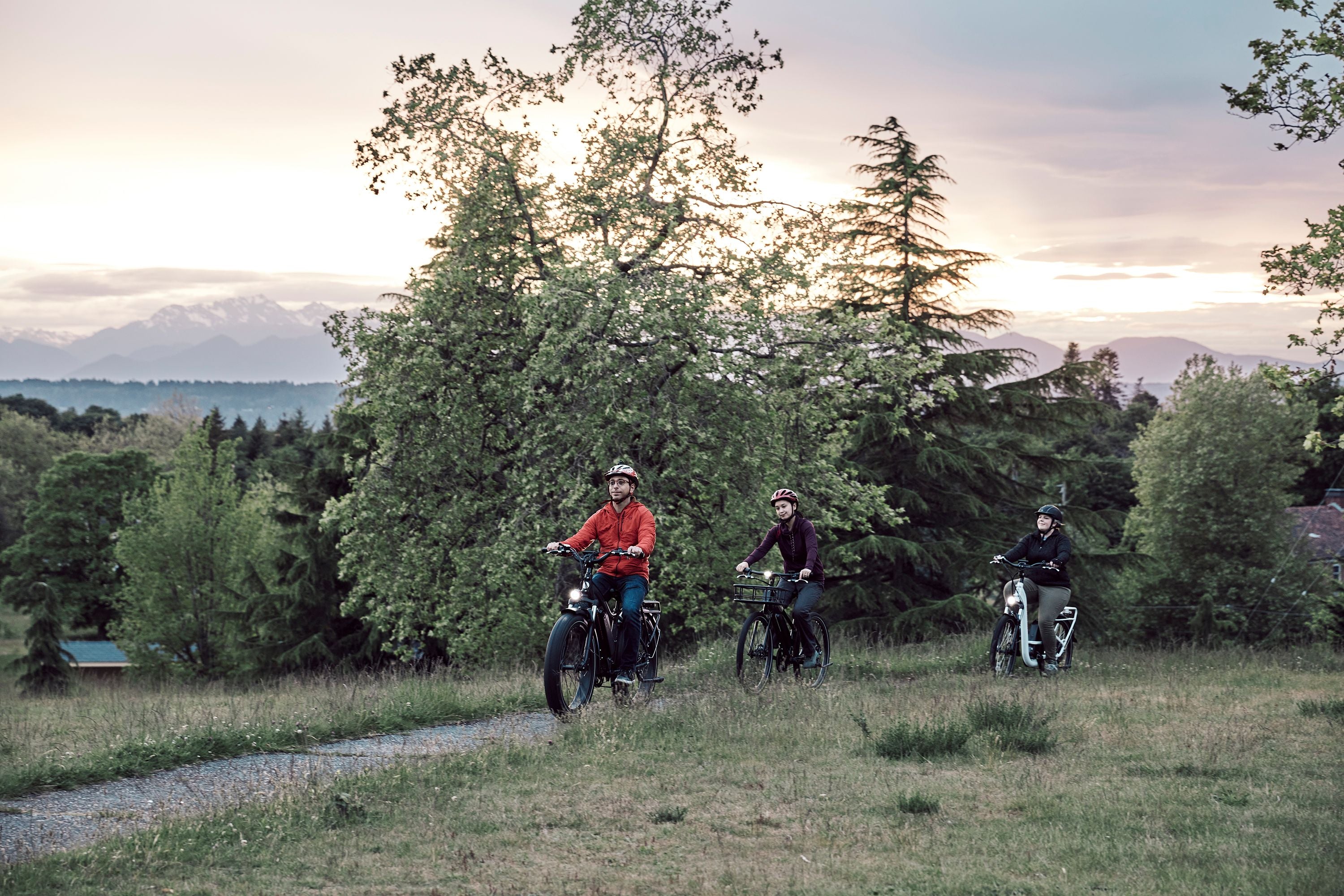 Three individuals ride their ebikes on a path.