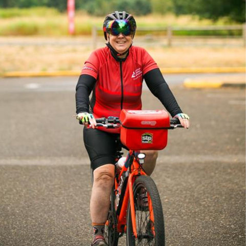 A woman wearing red cycling gear rides a red Rad electric bike.