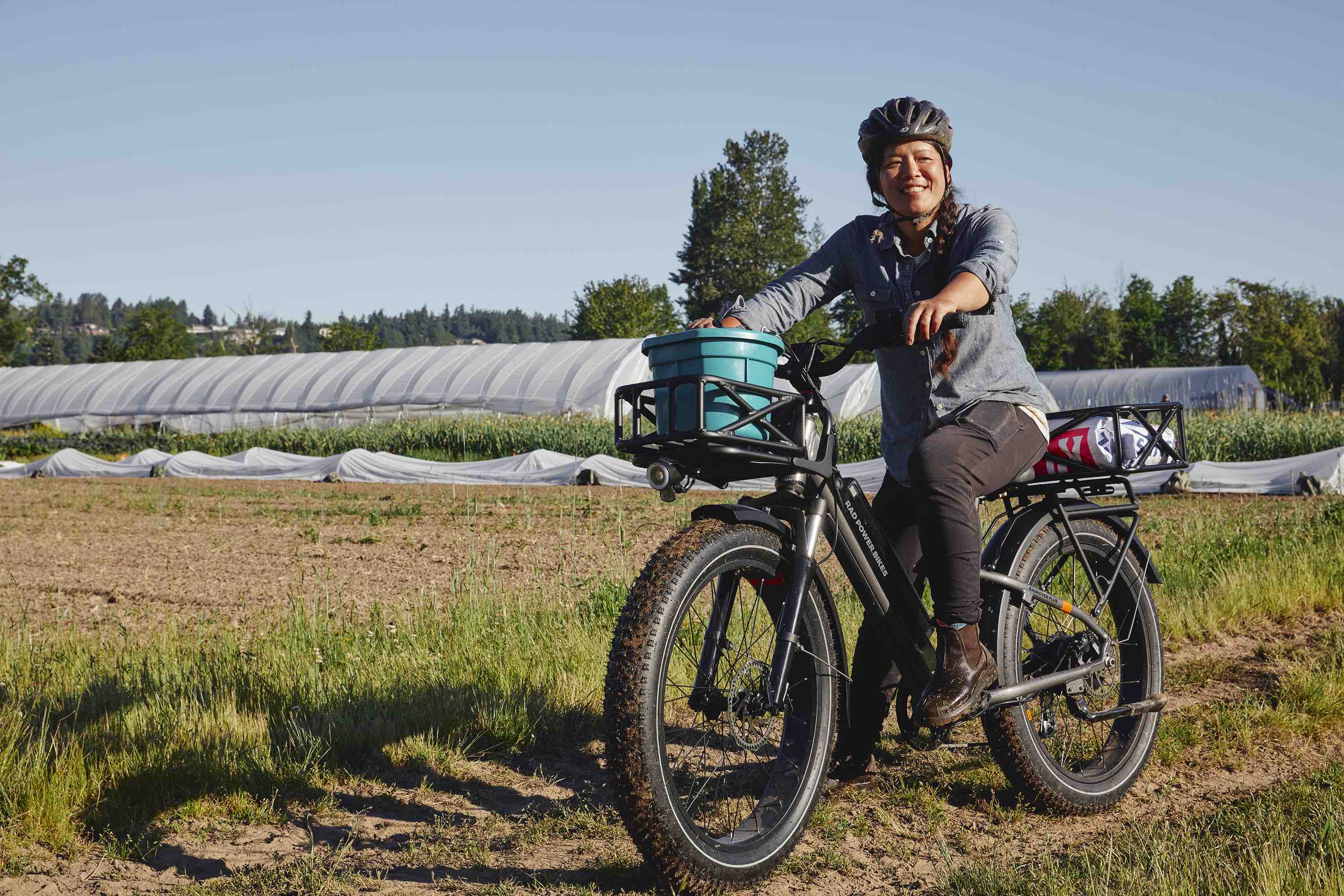 A woman rides a RadRover 6 Plus on a farm.