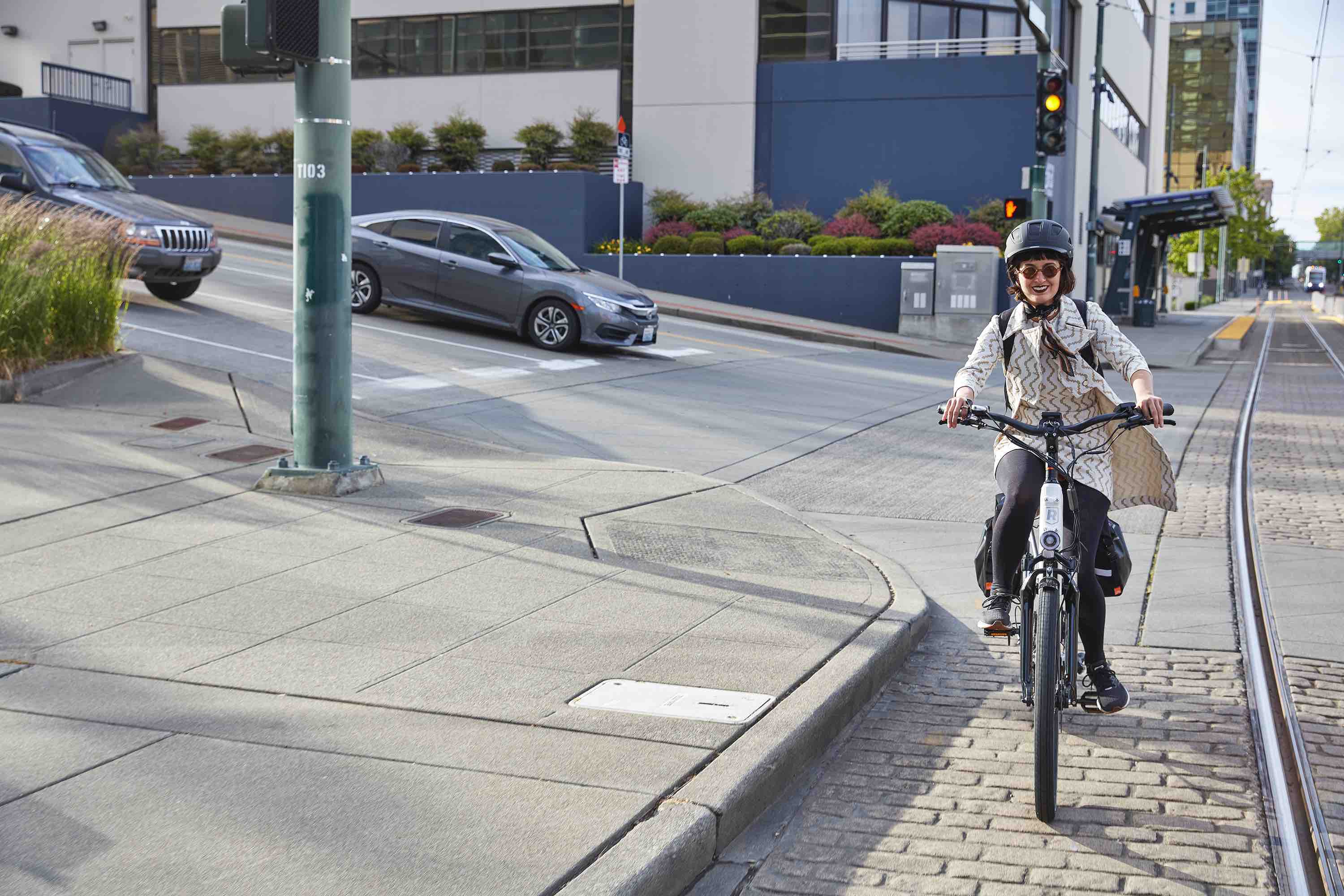 A woman rides an electric commuter bike down a bike lane.