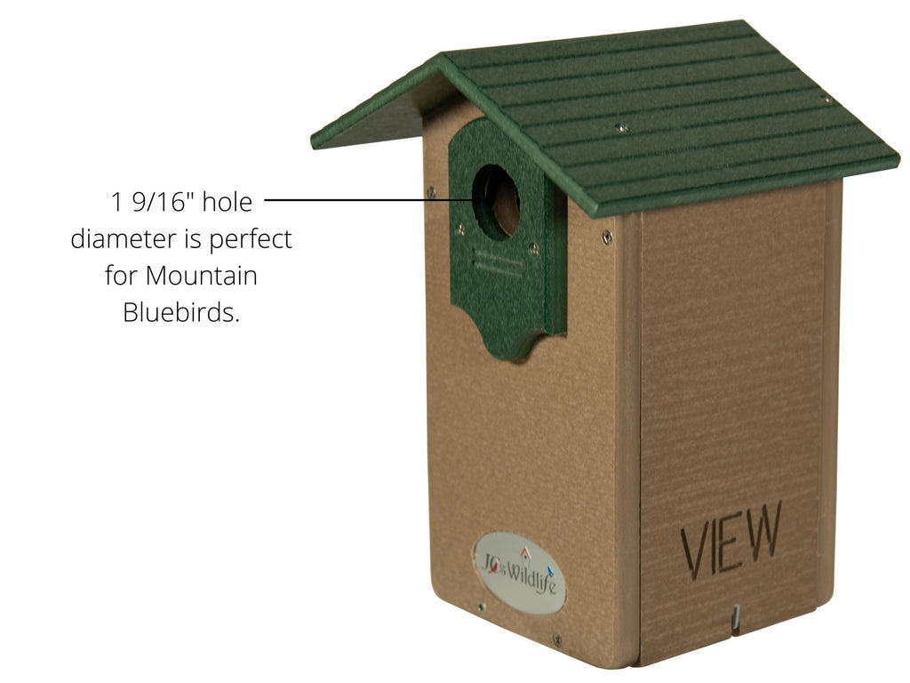 Close-up of a wooden birdhouse with a green roof. The entrance hole is labeled with text stating '1 9/16" hole diameter is perfect for Mountain Bluebirds.' The side of the birdhouse has the word 'VIEW' and a logo reading 'JC's Wildlife.