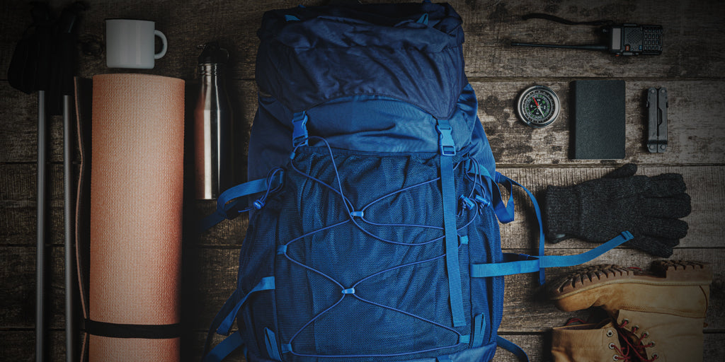 image of a large blue a thermos and various other hiking gear on a dark wooden floor