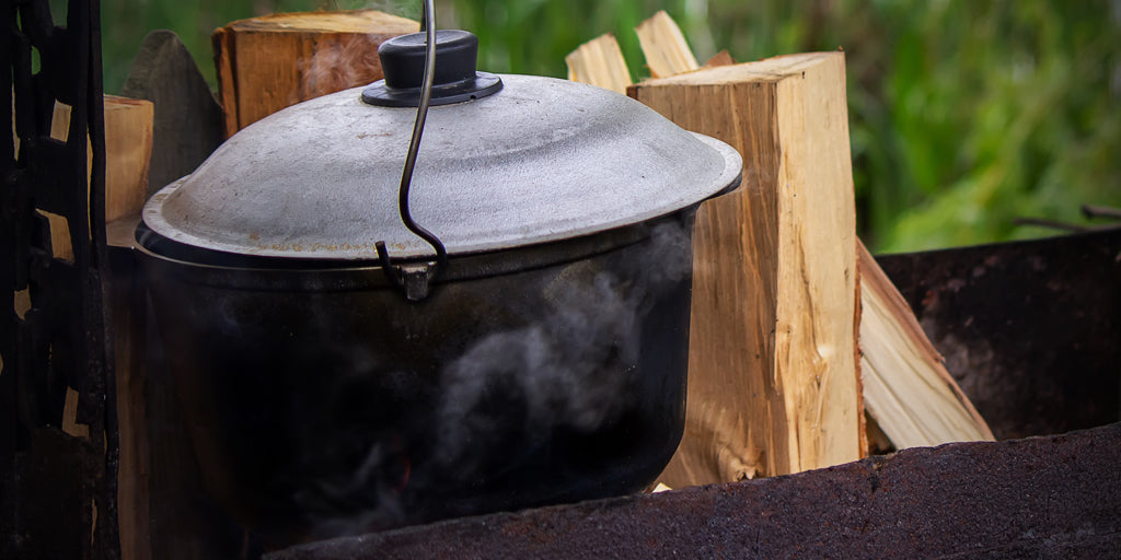 Image of a kettle and stack of wood ready for a Campfire Cuisine