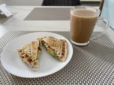 A toasted snack filled with meat and salad served with a cup of tea