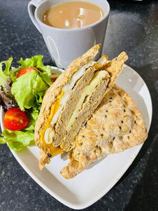 A toasted snack filled with cheese and egg. Served with salad and a cup of tea. 